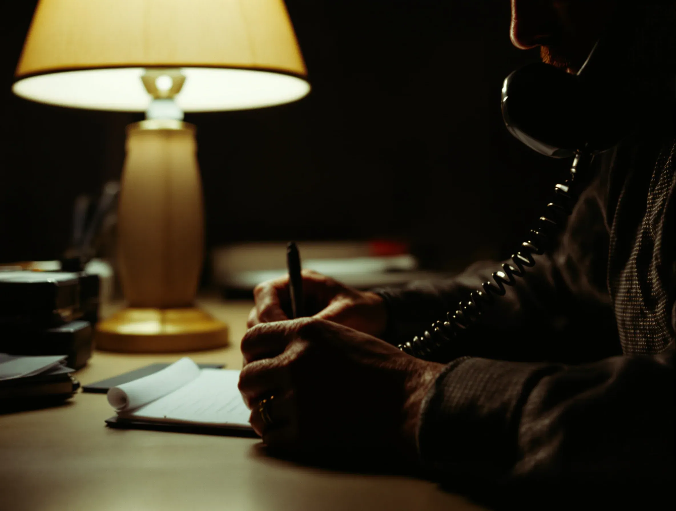 Bail agent writing notes at a desk while taking a call from a family